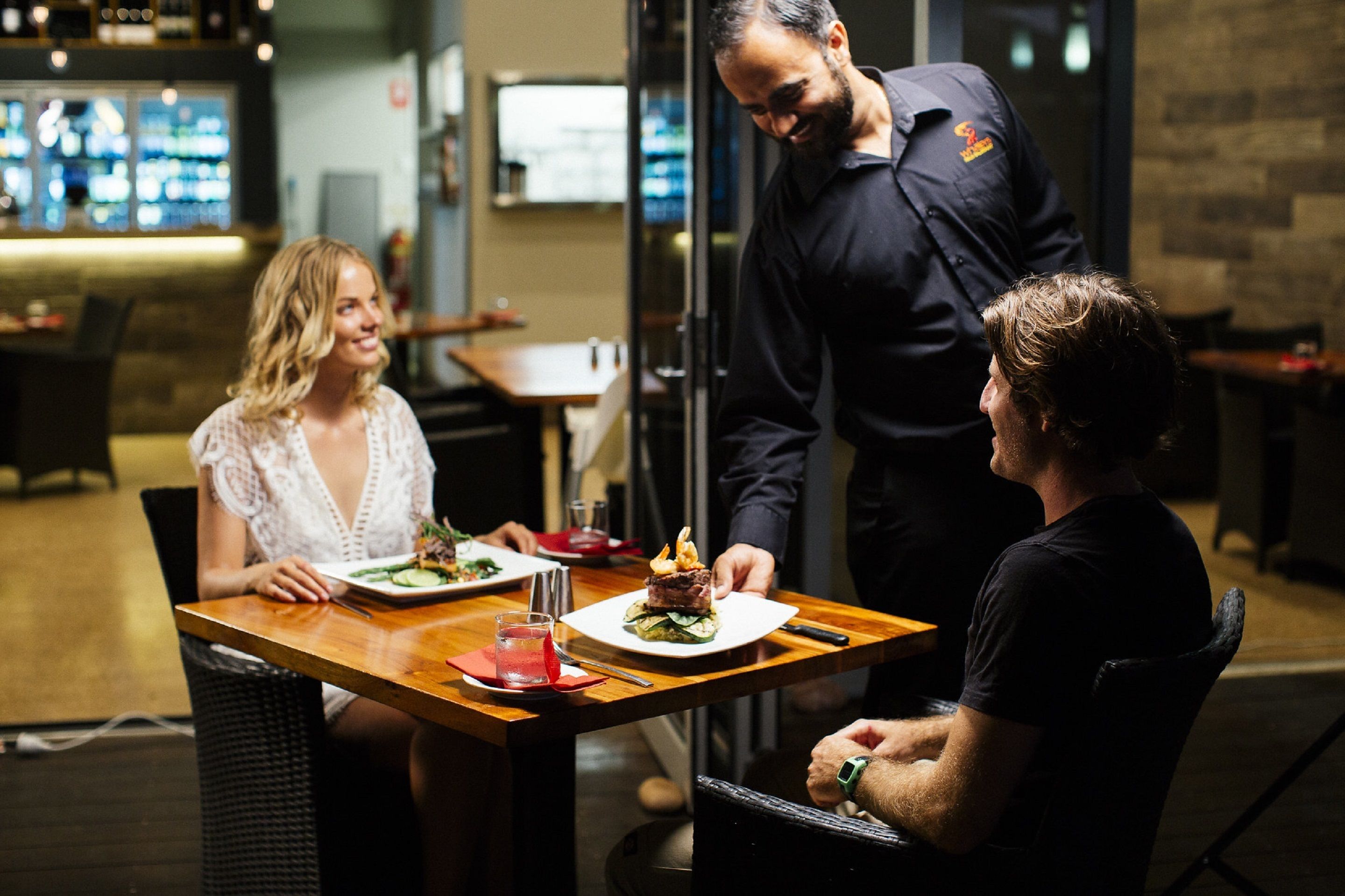 A restaurant setting with a wooden table, a plate of food, and a drink.