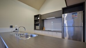 A modern kitchen with a stainless steel sink, a built-in oven, and a refrigerator. - Exmouth Escape Resort (Exmouth)