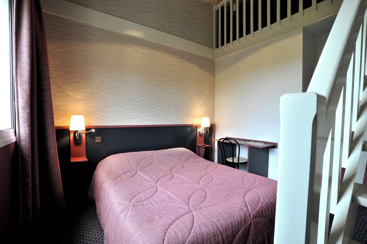 A hotel room with a bed, two bedside lamps, a desk, and a window with curtains.
