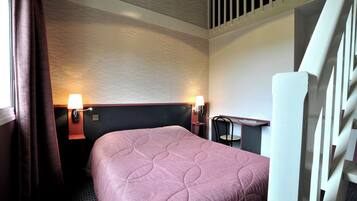 A hotel room with a bed, two bedside lamps, a desk, and a window with curtains.