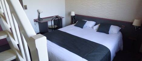 Una habitación de hotel con cama, escritorio, silla y lámpara.