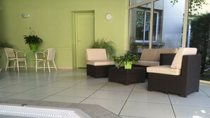 A sunlit indoor patio with a hot tub, wicker furniture, and potted plants. - Brit Hotel Confort Villefranche de Rouergue (Villefranche-de-Rouergue)