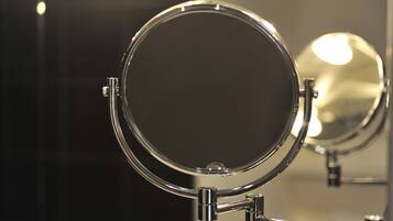 Un miroir de salle de bain avec un cadre en chrome et une forme ronde.