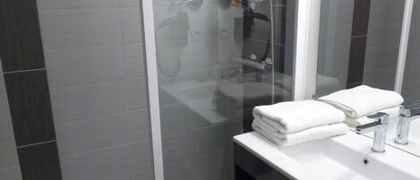 A modern bathroom with a glass-enclosed shower, a white sink, and a mirror above it.