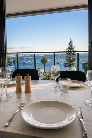 Mesa de comedor para dos con vista a un puerto deportivo y un árbol.