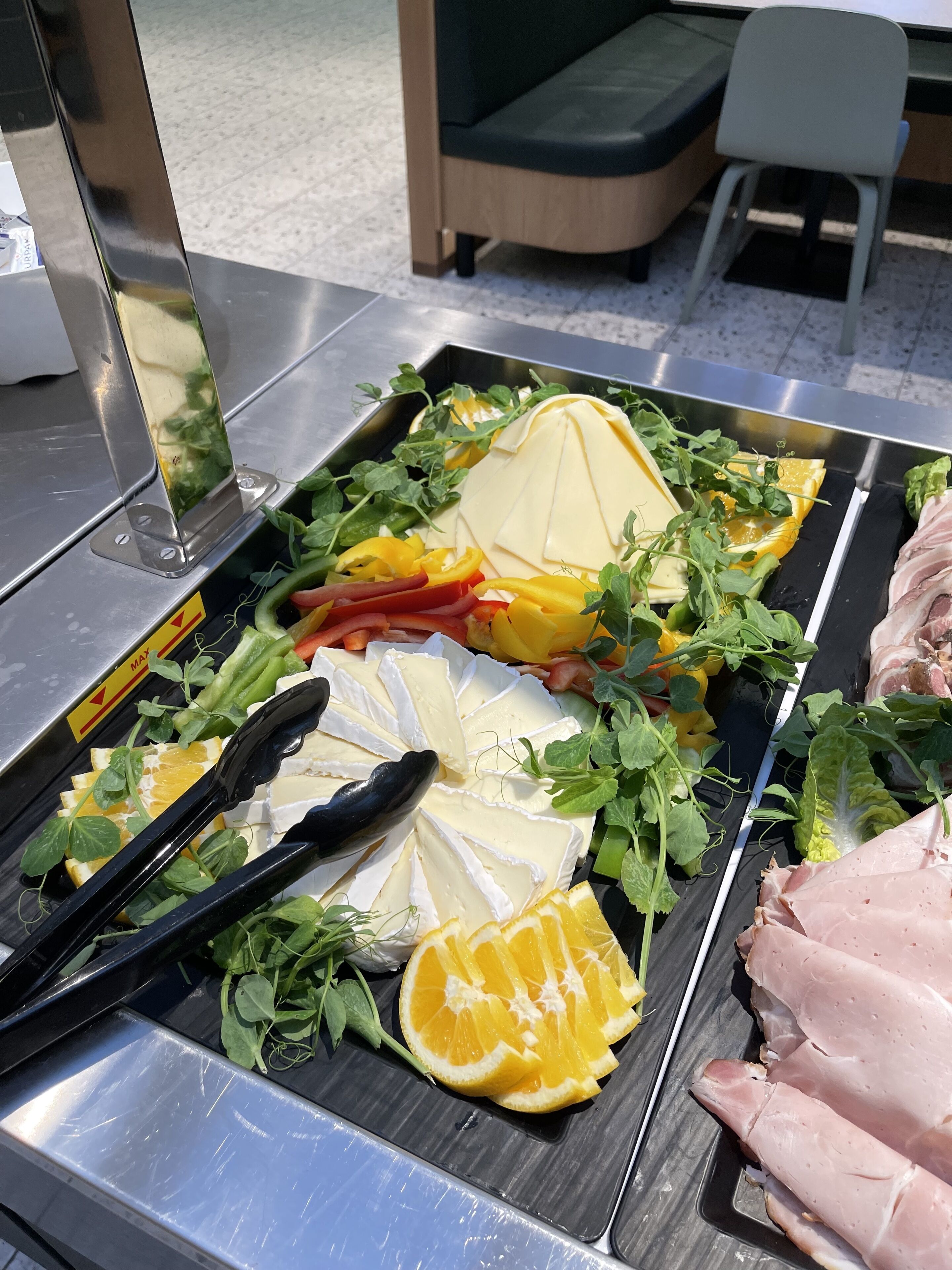 Una mesa de buffet con diversas opciones de comida, incluyendo queso, frutas y verduras.