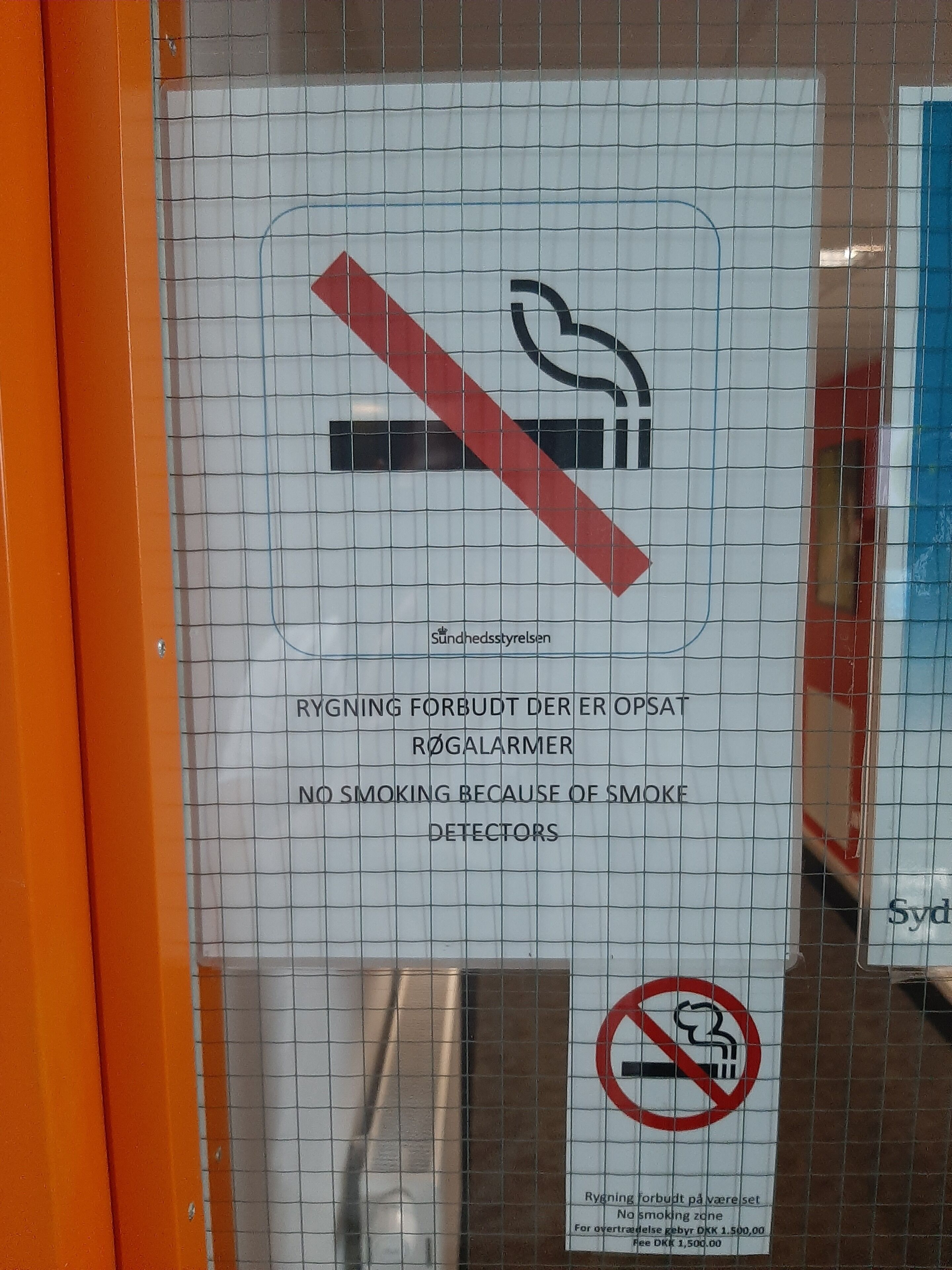 A no-smoking sign with text in multiple languages and a fine for violations.