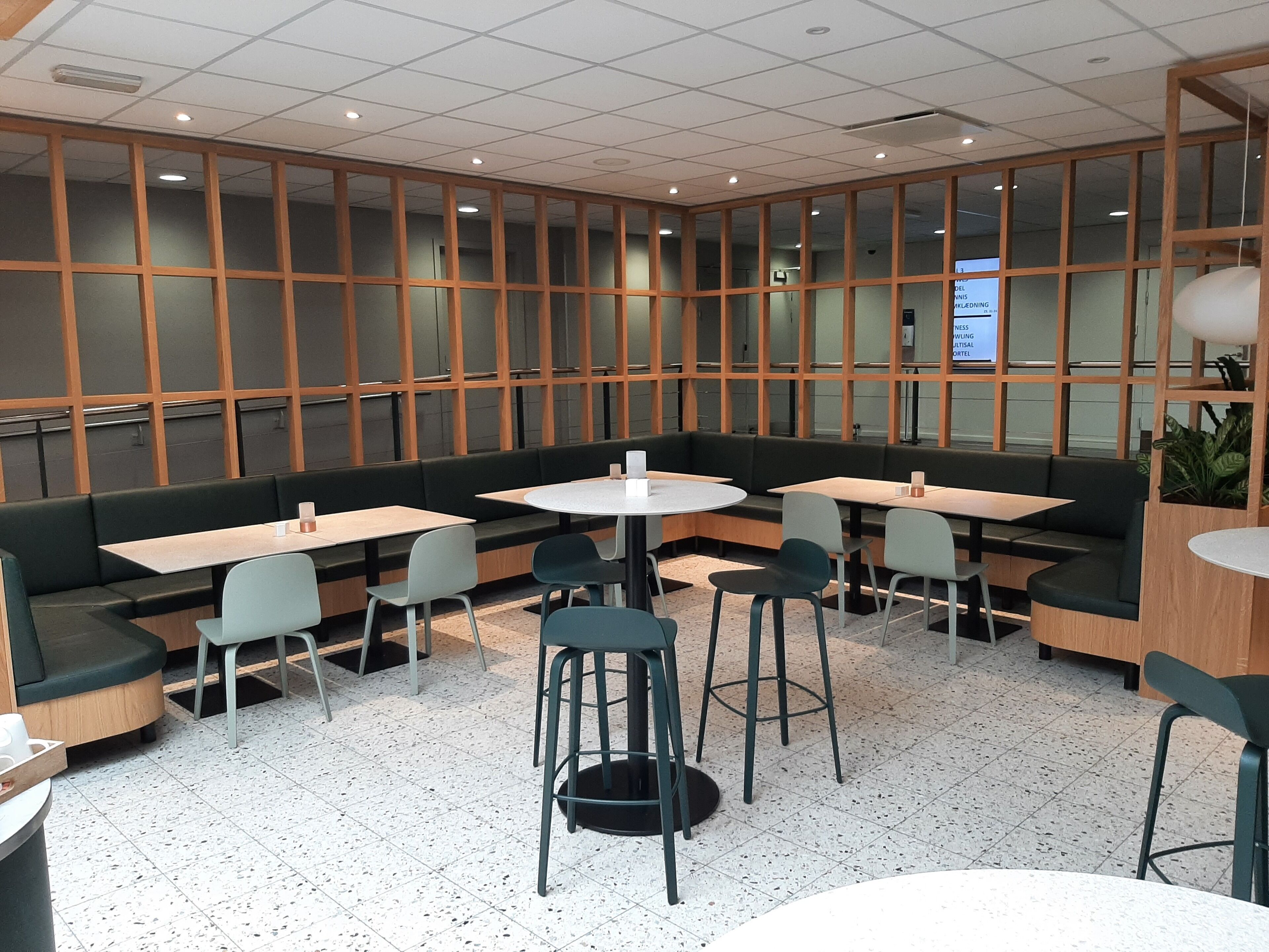 A modern dining area with booths and tables, featuring a mix of seating options and a tiled floor.