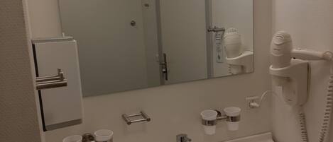 A bathroom with a white sink, a mirror, a hairdryer, and a telephone.