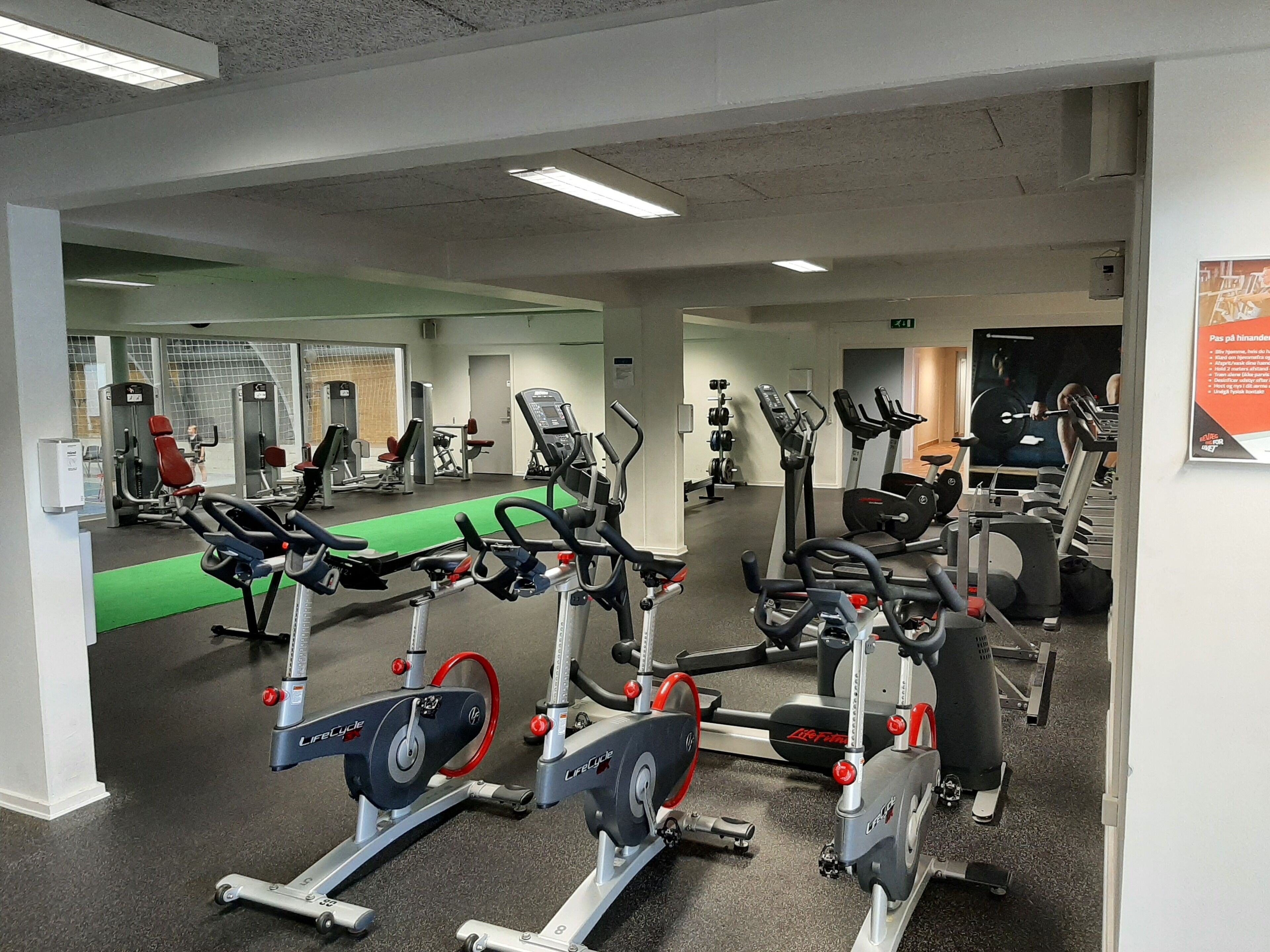 A gym with various exercise equipment including treadmills, stationary bikes, and weight machines.
