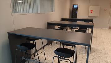 A conference room with a long table, four chairs, and a charging station.