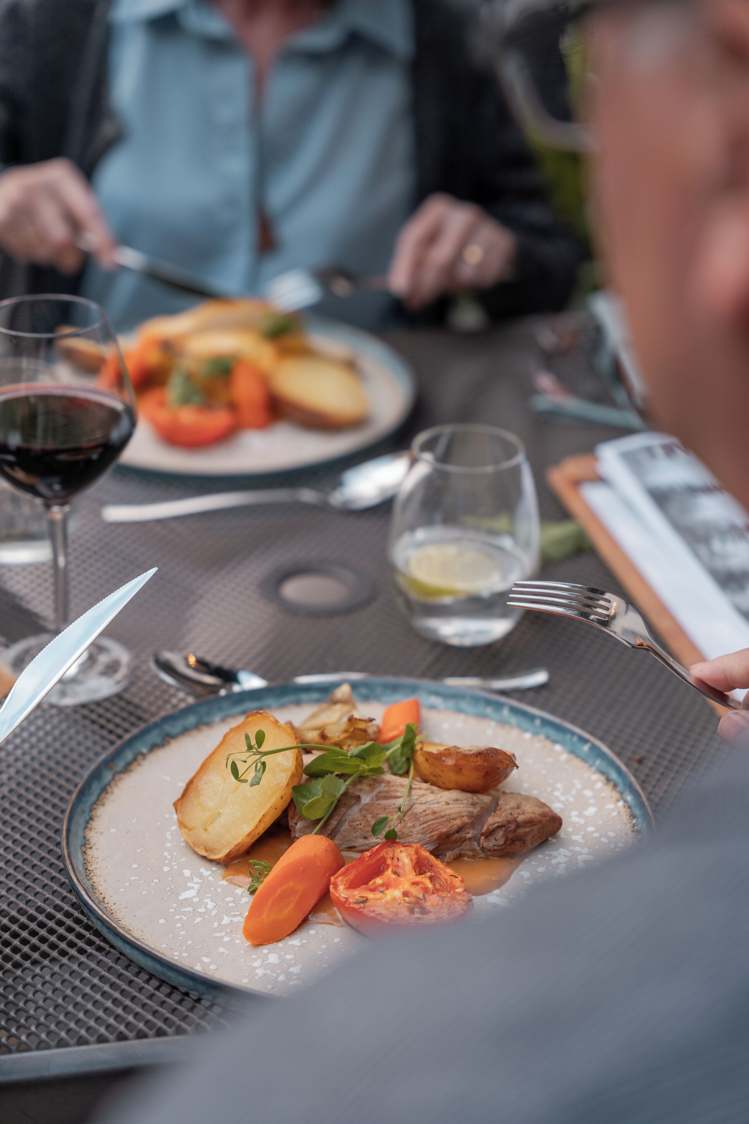 A dining table with plates of food, cutlery, and glasses.