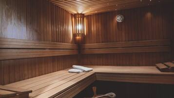 Eine Sauna mit Holzbänken, einer Wanduhr und einem Holzeimer.