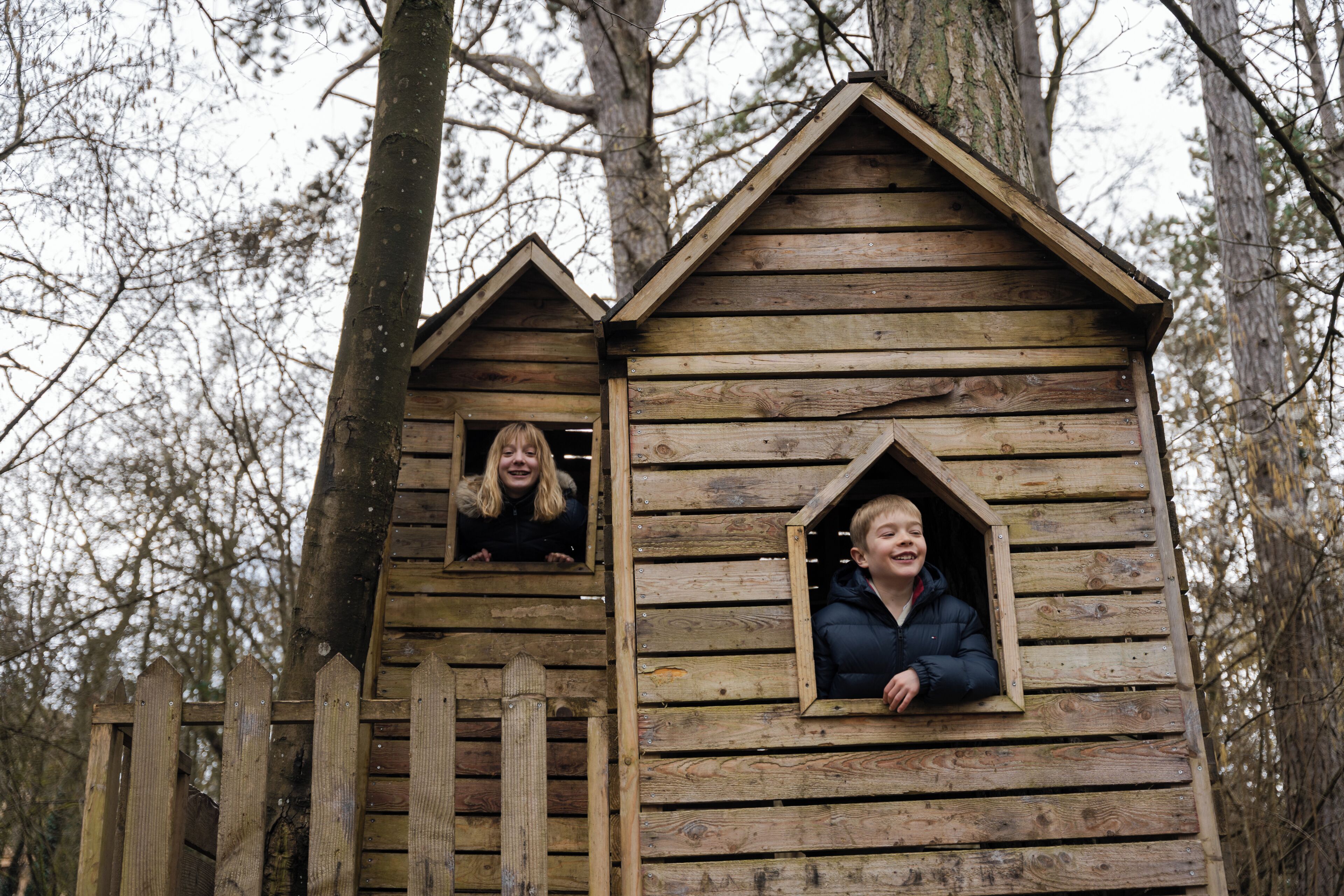A wooden cabin with a sloped roof and a picket fence.