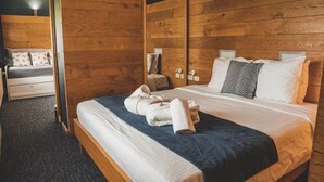 Een slaapkamer met houten lambrisering, een bed, kussens en een nachtkastje.