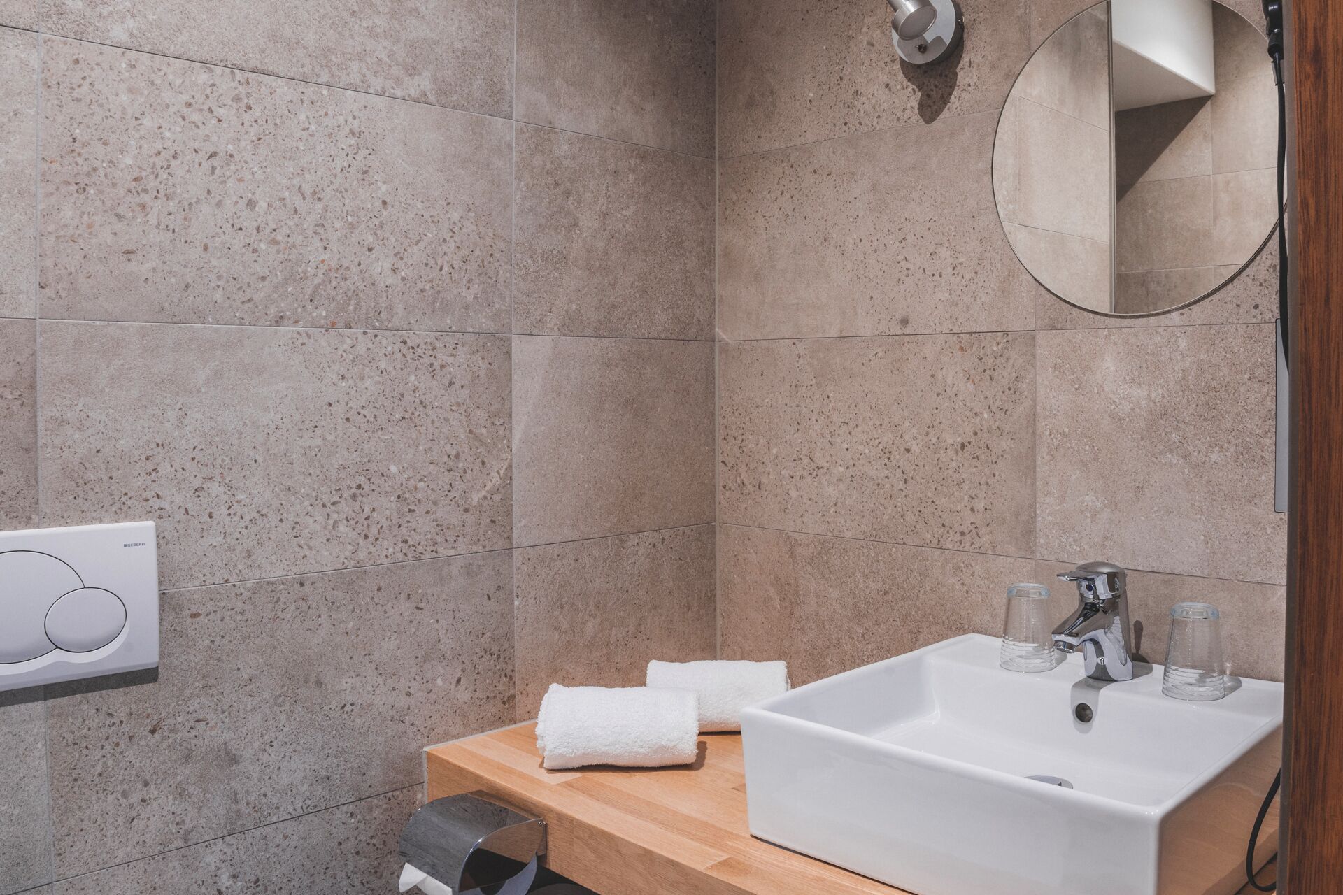 A bathroom with a white sink, two faucets, a mirror, and a towel rack.