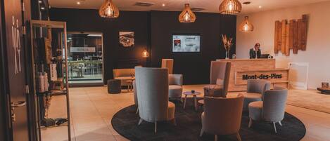 A hotel lobby with a reception desk, seating area, and a large screen displaying information.