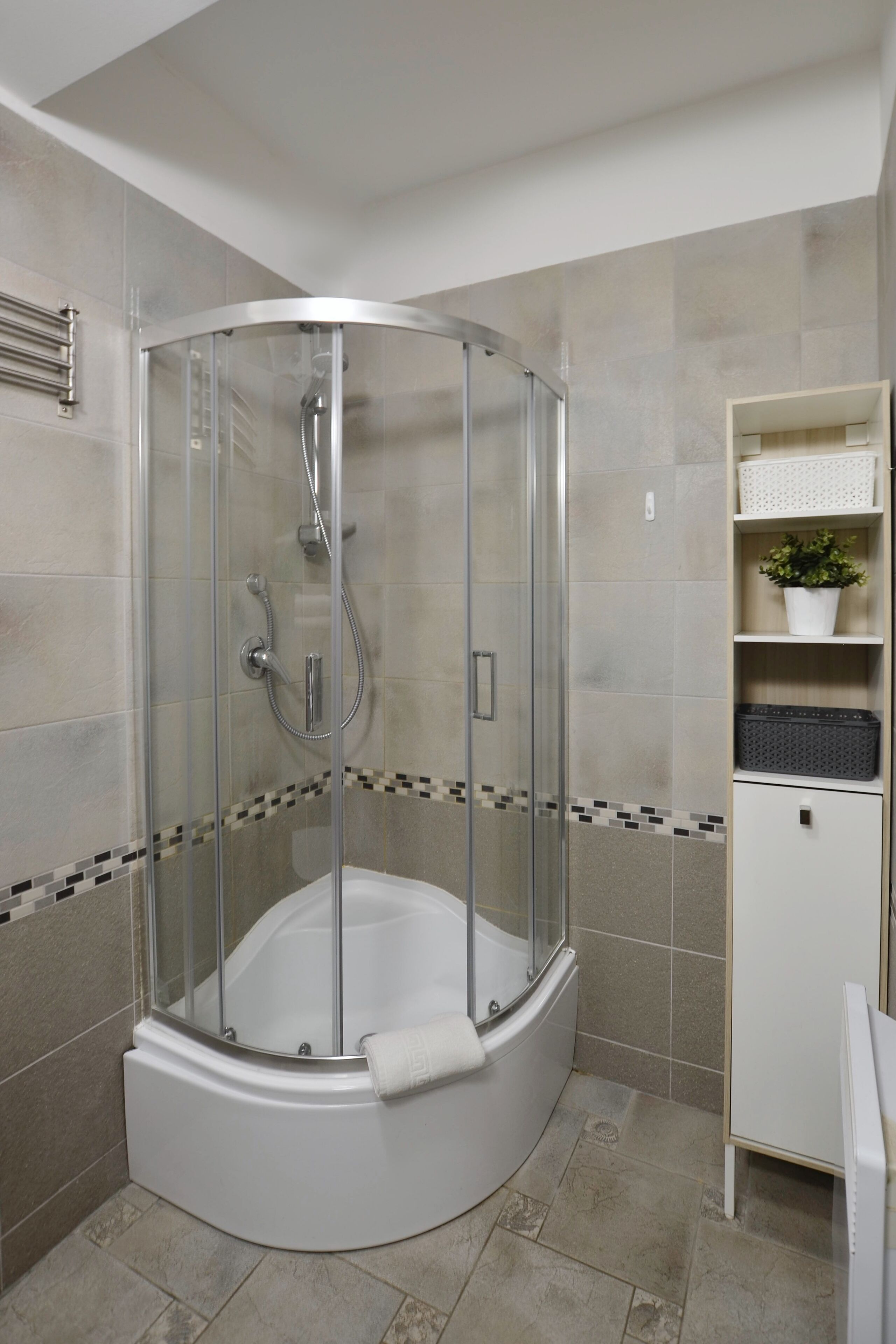 A modern bathroom with a glass-enclosed shower, a white bathtub, and a tiled floor.
