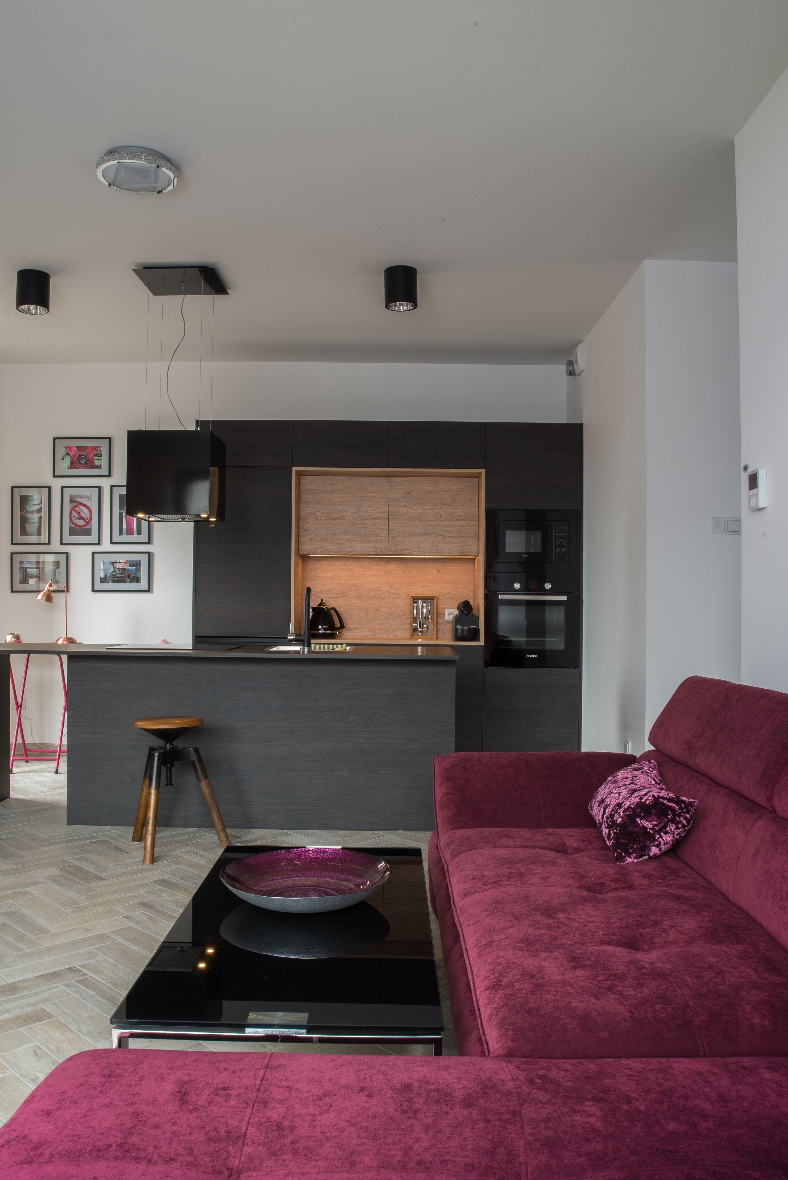 A modern kitchen with a central island, a red sofa, and a dining area with a table and chairs.