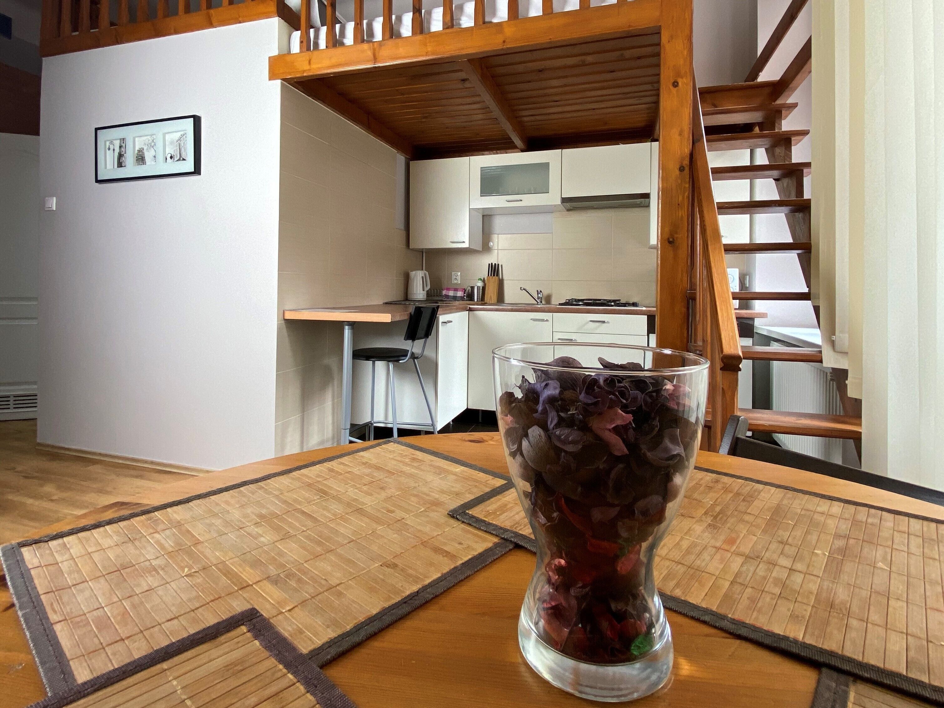 Una sala de estar con una mesa de centro de madera, una cocina al fondo y una escalera.