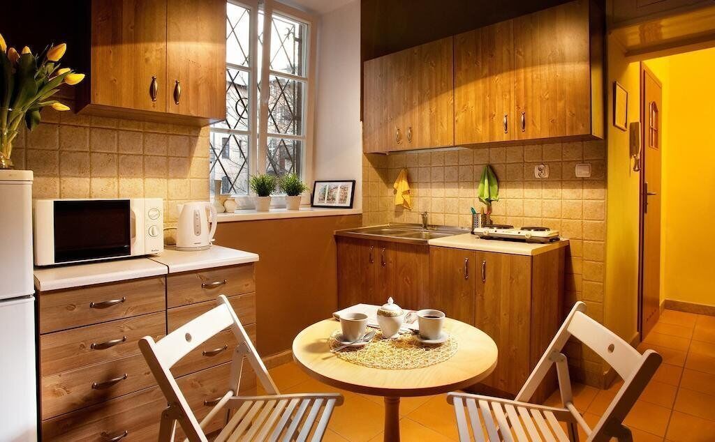 Eine kompakte Küche mit Holzausstattung, einer Mikrowelle, einem Spülbecken und einer Essecke mit zwei Stühlen und einem Tisch.