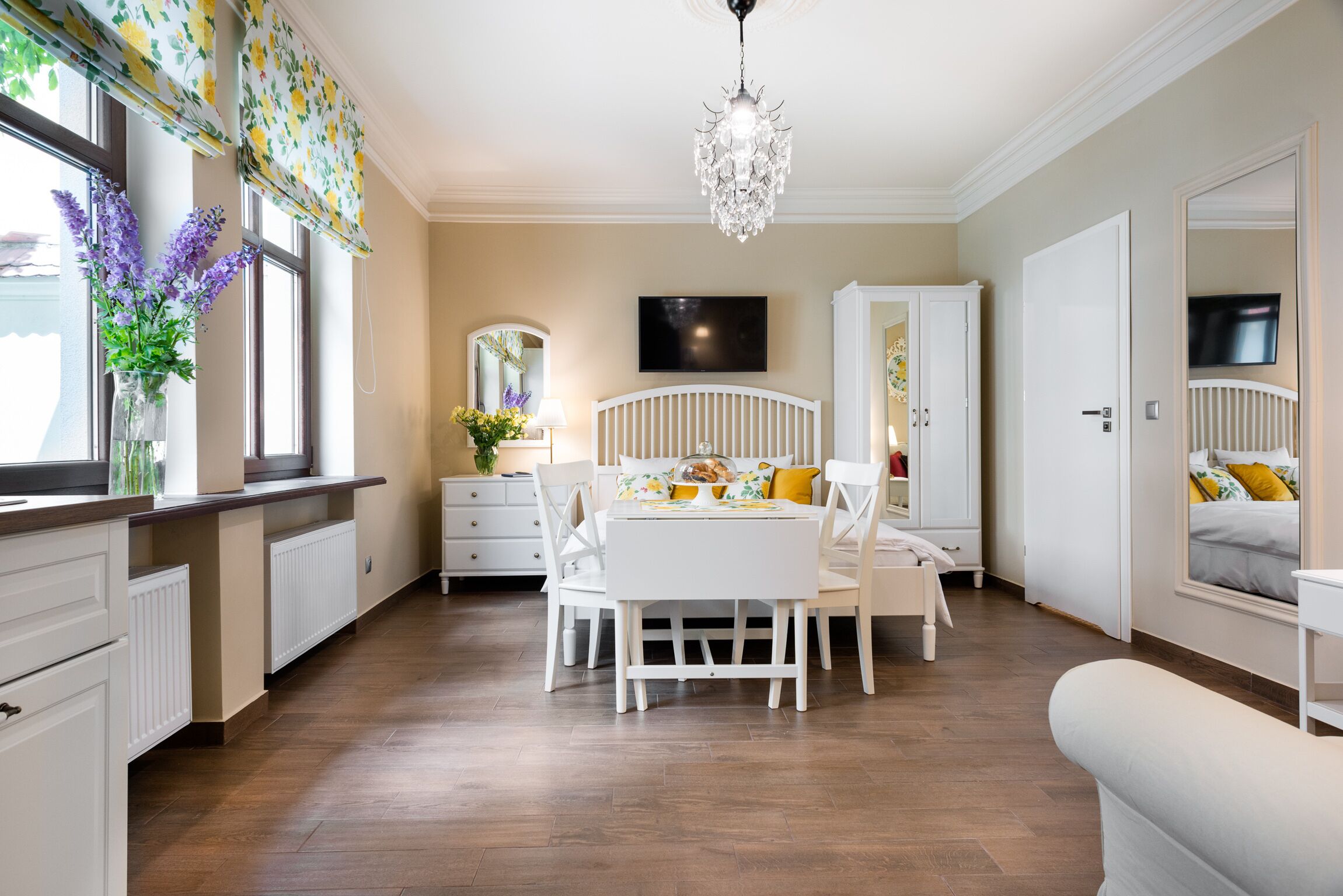 A bedroom with a bed, bedside table, dresser, and a large mirror.