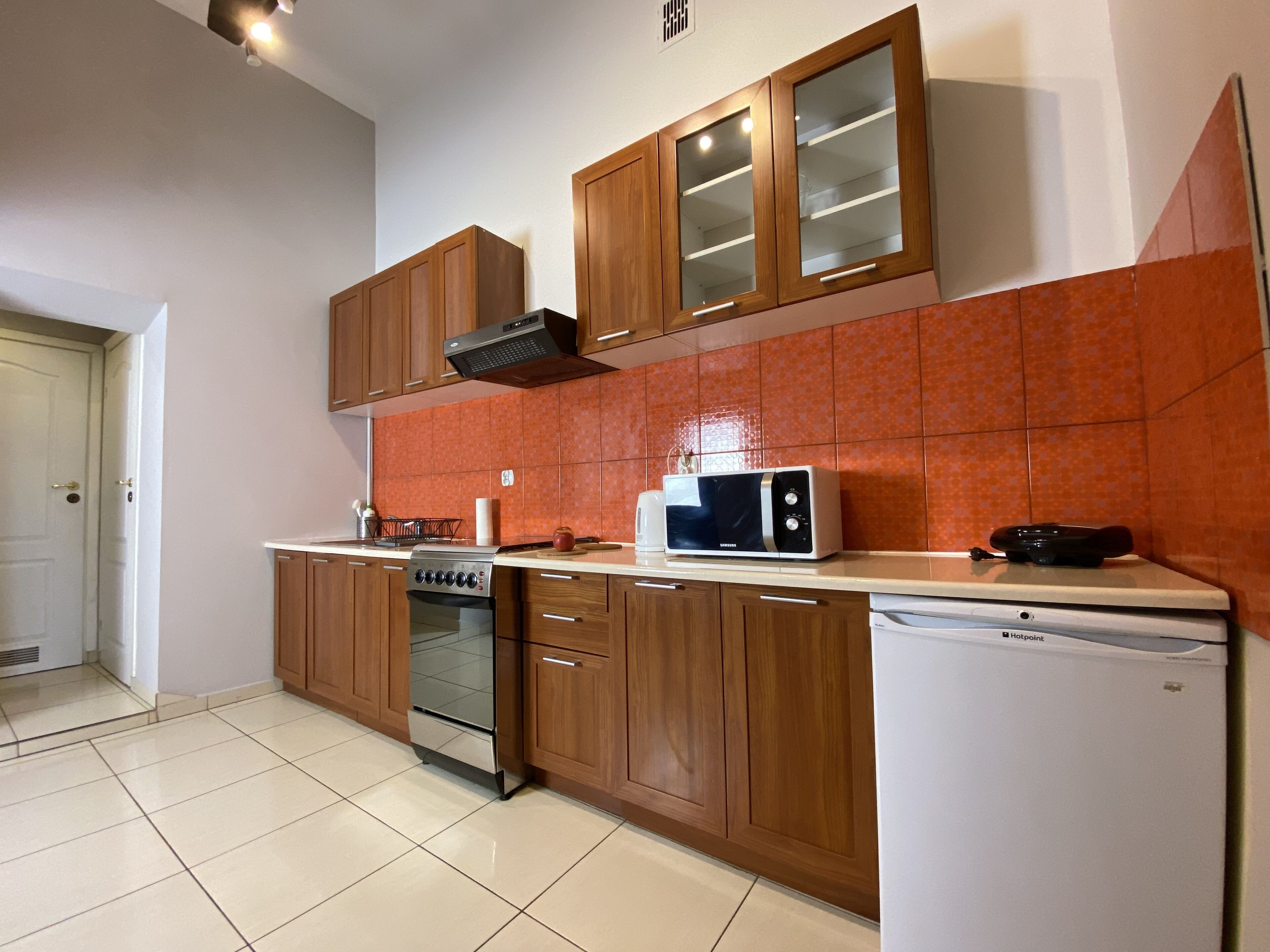 Una cocina con armarios de madera, microondas, lavavajillas y estufa.