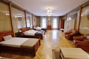 Hotellihuone, jossa on kaksi sänkyä, puulattia, ruskea nahkainen nojatuoli ja puinen kaappi.