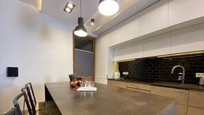 A modern kitchen with a large island, black backsplash, and stainless steel appliances. - P&J Apartments (Kraków)