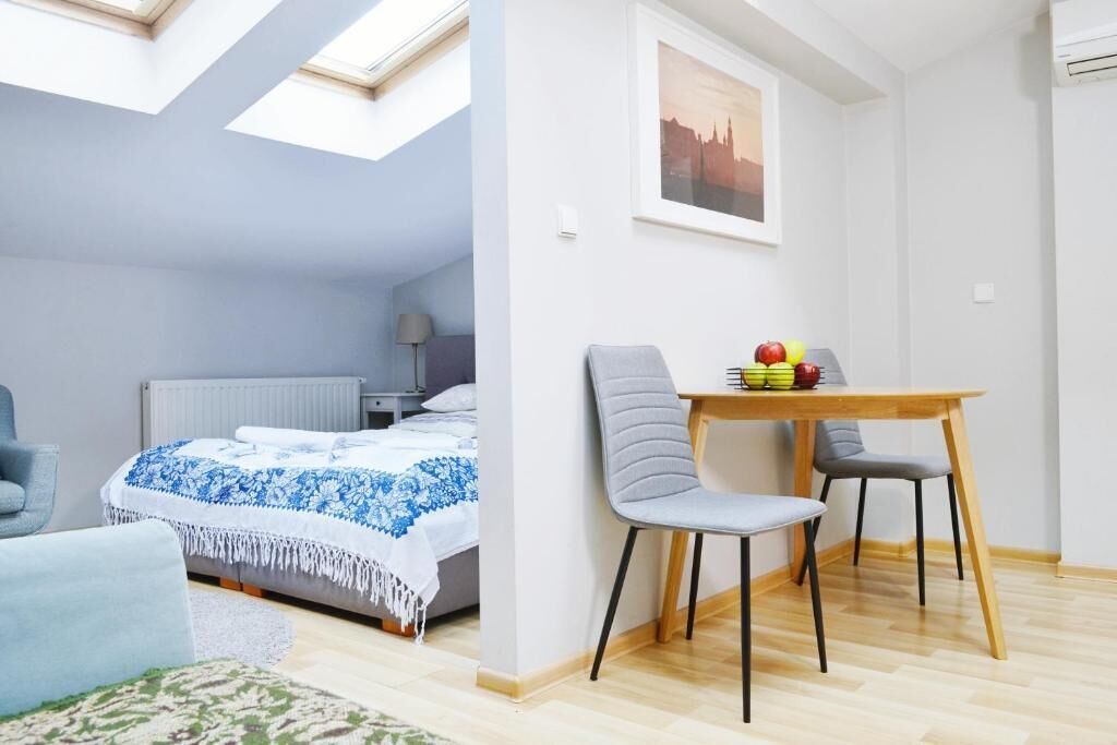 Ein gemütliches Schlafzimmer mit Dachfenster, einem Bett mit blauer und weißer Bettdecke, einem kleinen Tisch mit Obst und einem grauen Sessel.