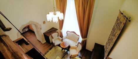 A room with a wooden staircase, a chandelier, a round table, and a sofa.