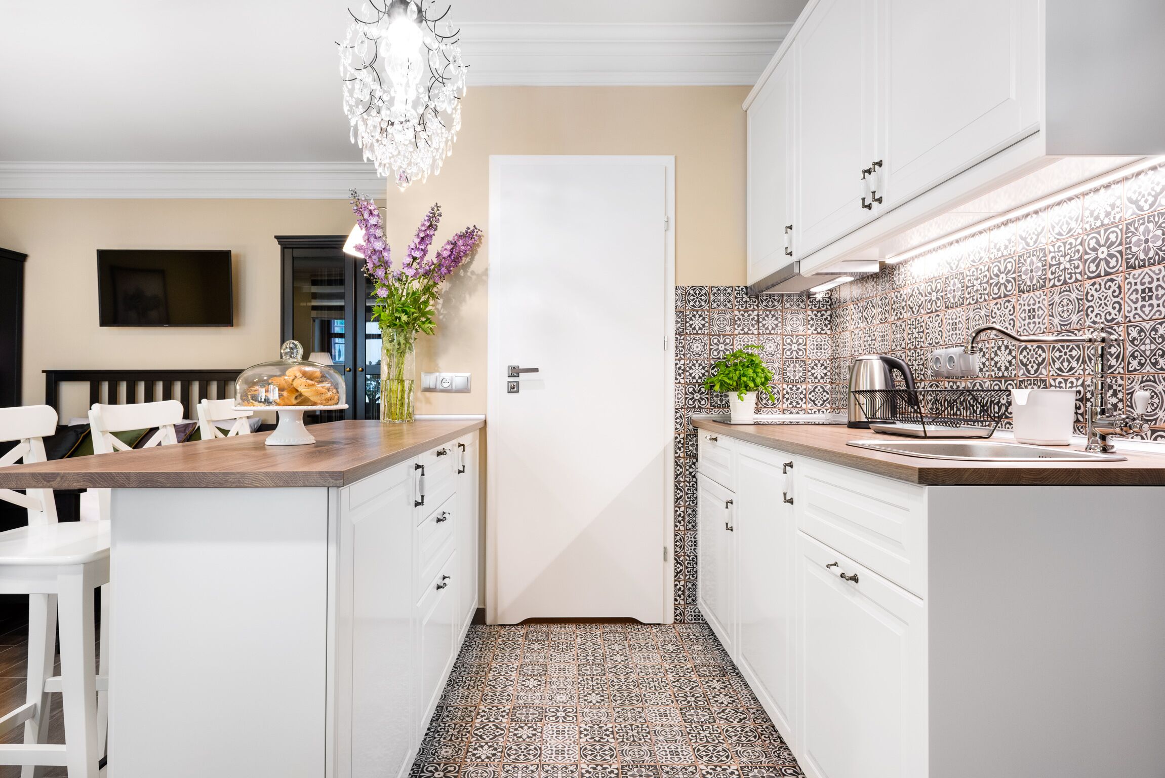Una cocina moderna con armarios blancos, encimera de madera y salpicadero estampado.
