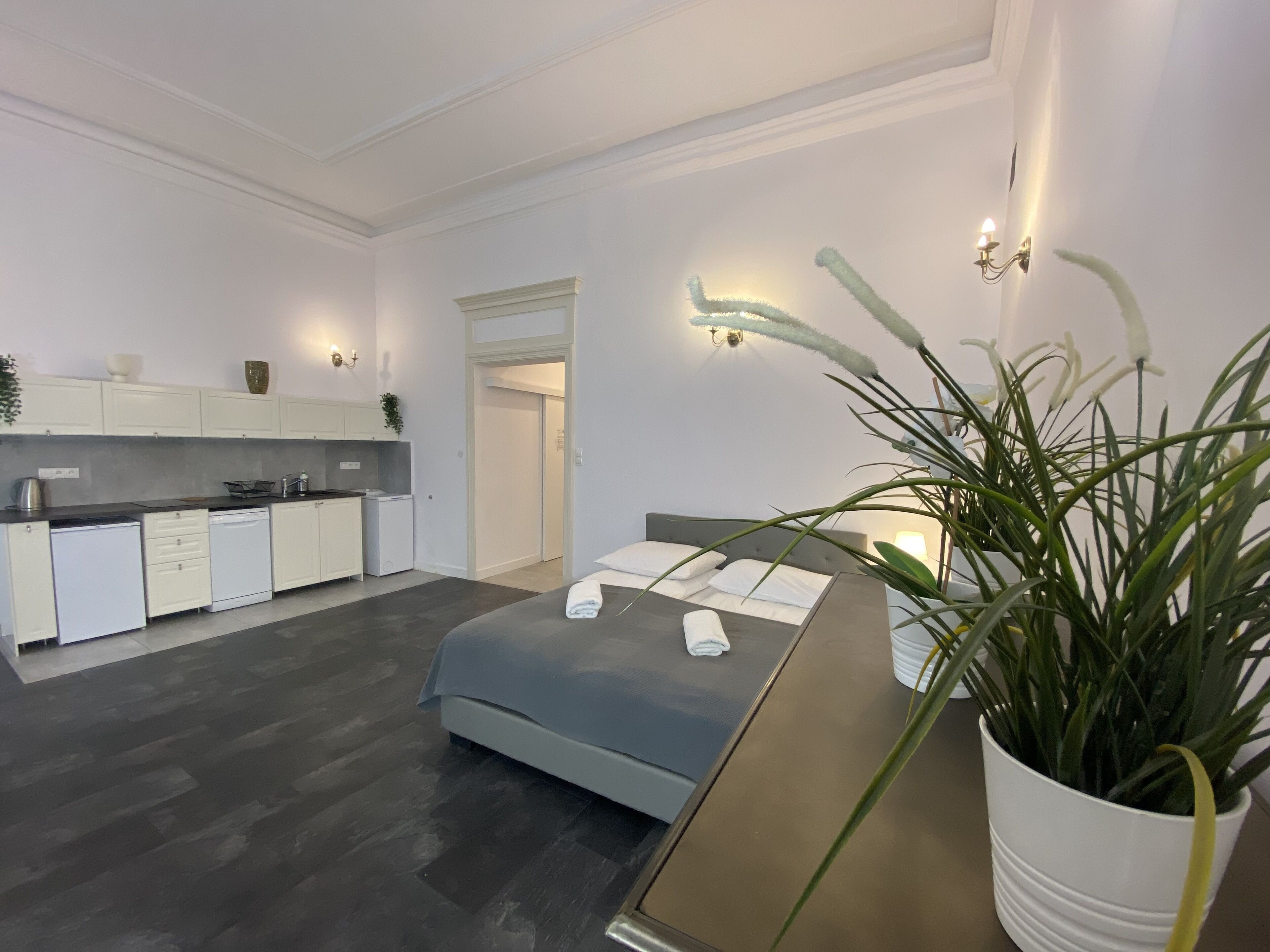 A modern bedroom with a bed, bedside table, and a potted plant.
