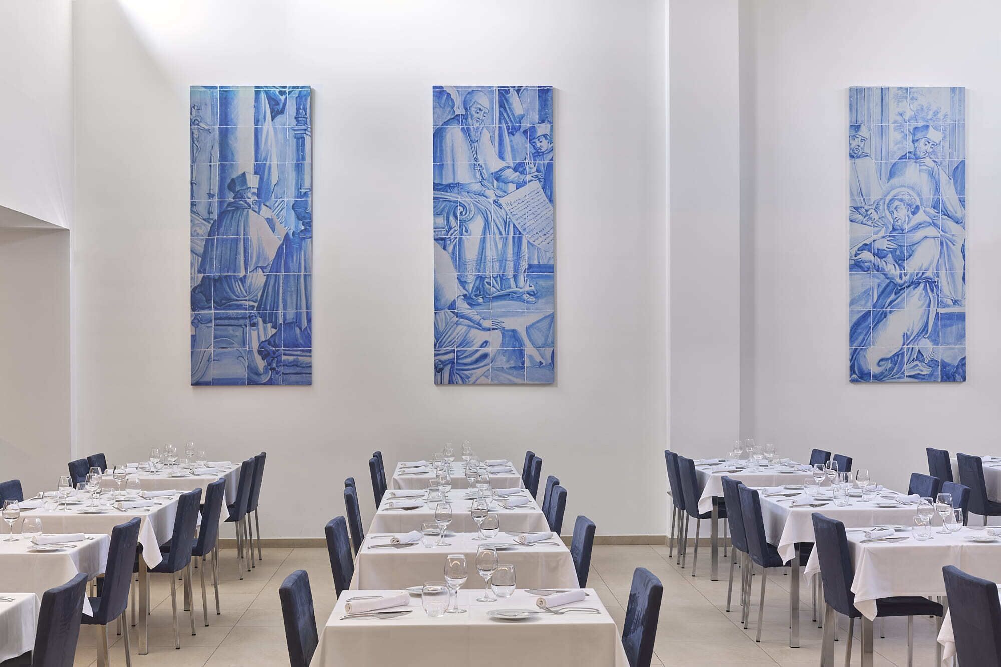 A dining area with tables set for service, blue wall art, and a clean, modern interior.