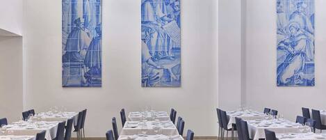 A dining area with tables set for service, blue wall art, and a clean, modern interior.
