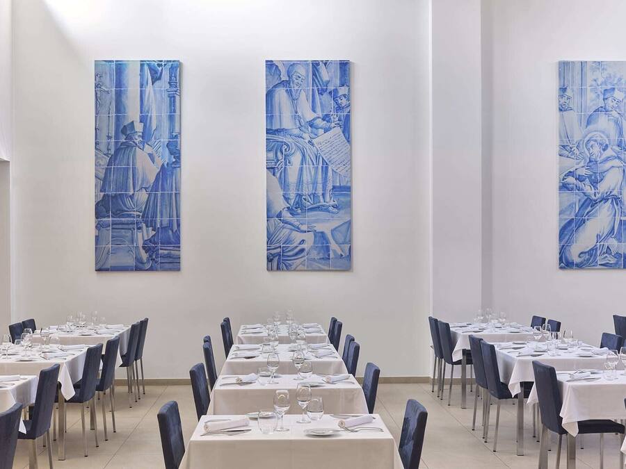 A dining area with tables set for service, blue wall art, and a clean, modern interior.