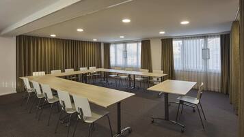 A conference room with a long table, white chairs, and a carpeted floor.
