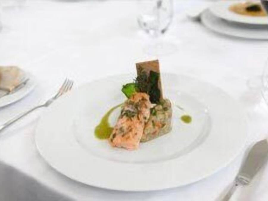 A white plate with a seafood dish, a fork, and a knife on a table.