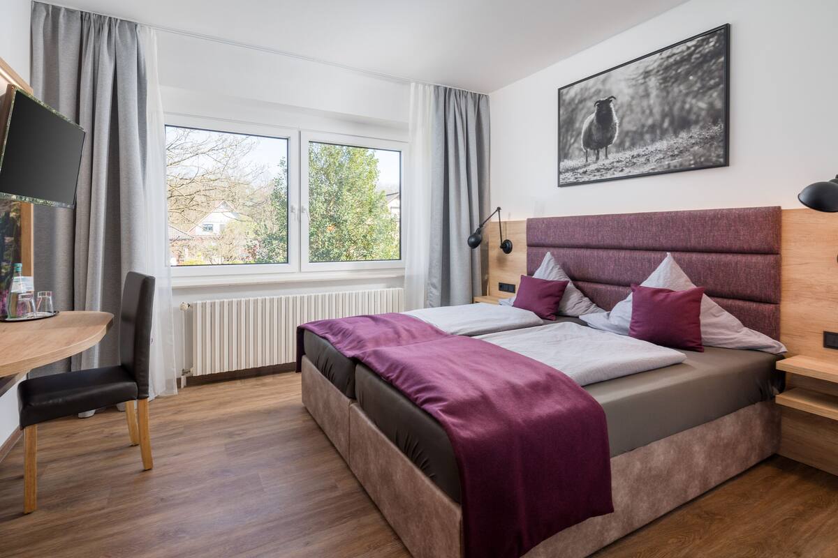 A modern bedroom with a large bed, a desk, and a chair.