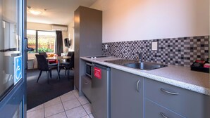 A modern kitchen with a large island, a built-in dishwasher, and a tiled backsplash. - 298 Westside Motor Lodge (Christchurch)