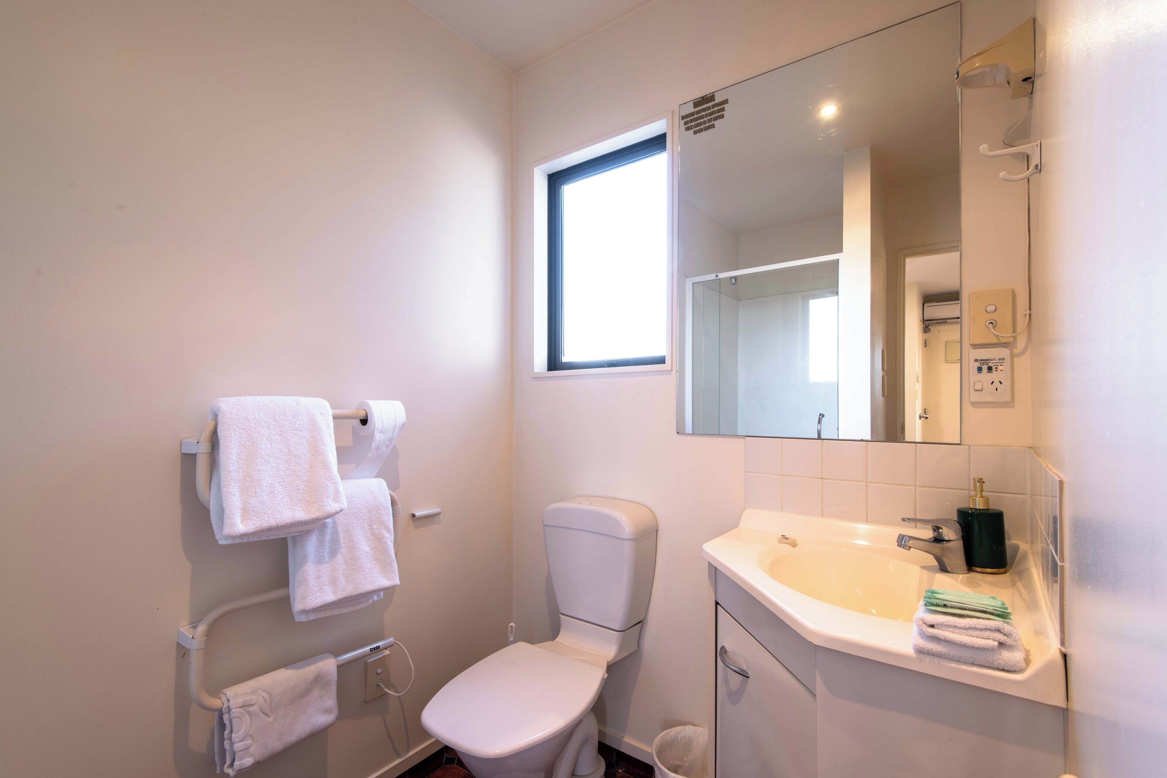 A small, clean bathroom with a toilet, sink, and a window.