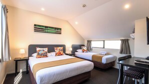 A hotel room with two beds, a desk, and a chair. There is a painting on the wall and a window with curtains. - 298 Westside Motor Lodge (Christchurch)