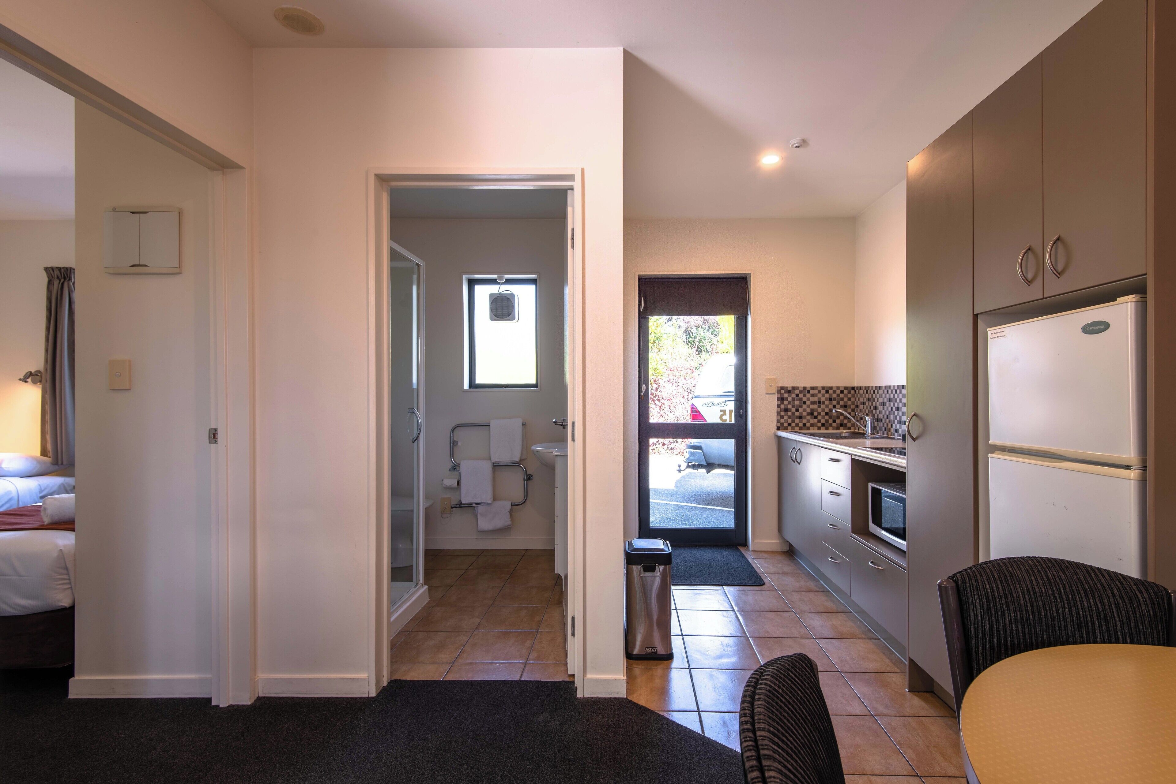 Une chambre d’hôtel de taille réduite, comprenant un lit, un petit coin salon et une kitchenette.