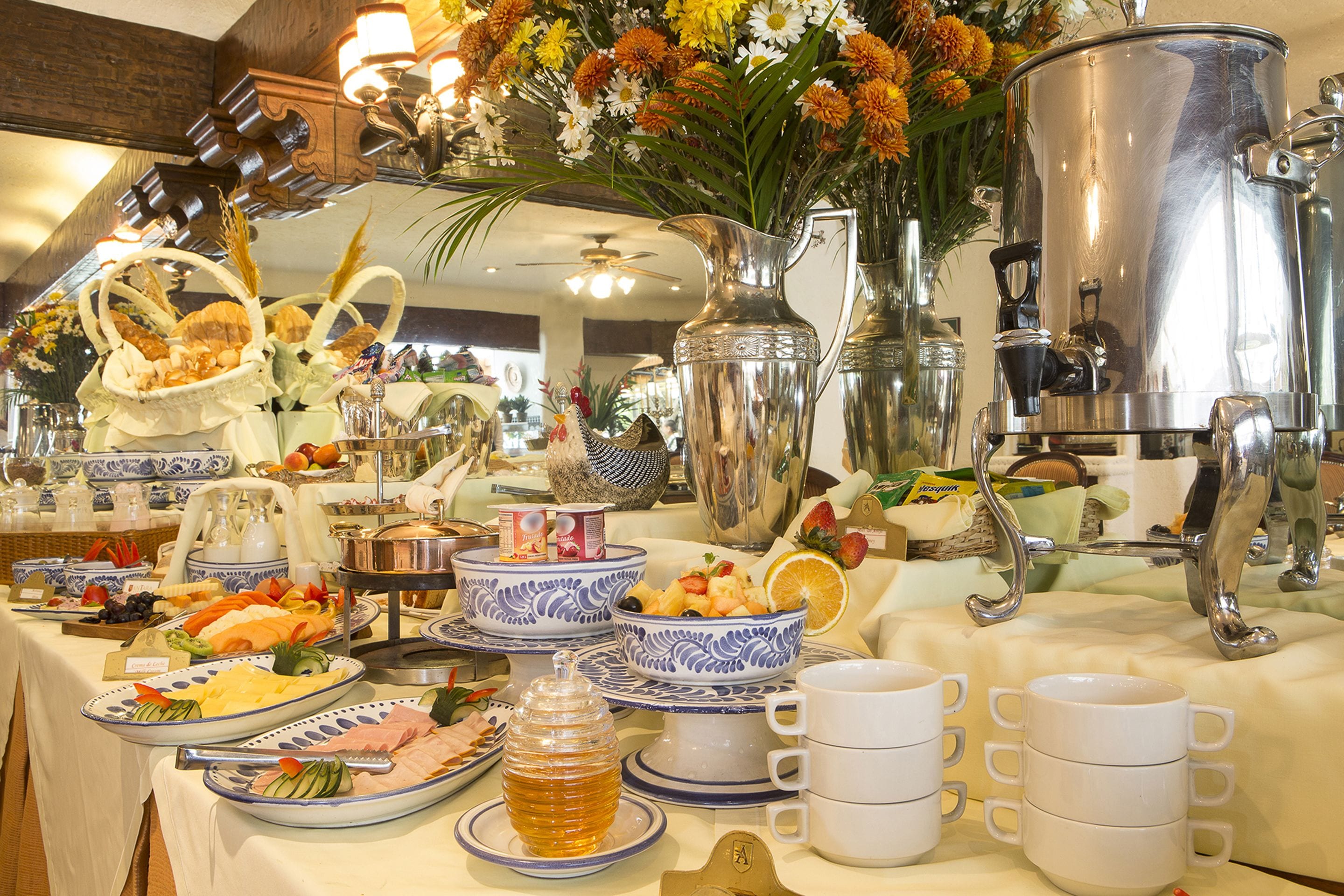 A buffet table with various food items, serving dishes, and a large silver pot.