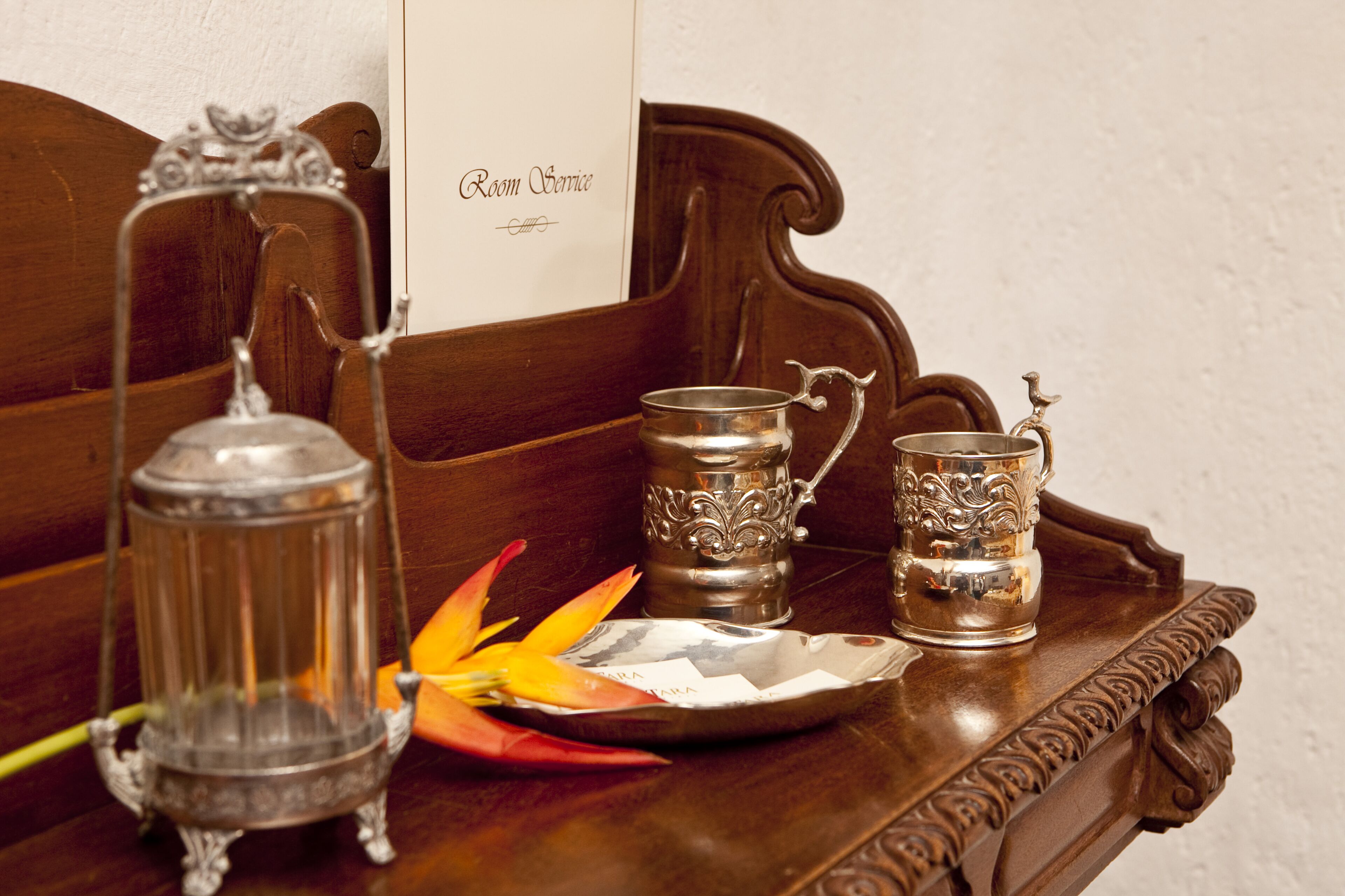 A wooden tray with a metal tray, a metal candle holder, and two metal cups with handles.