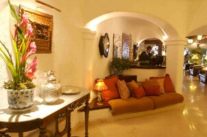 A lobby with a sofa, a table with a vase and a lamp, and a mirror on the wall.