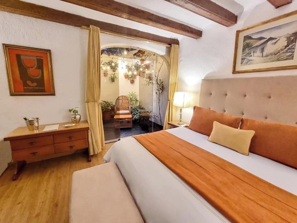 Een slaapkamer met een bed, een kaptafel, een spiegel en een schilderij aan de muur.