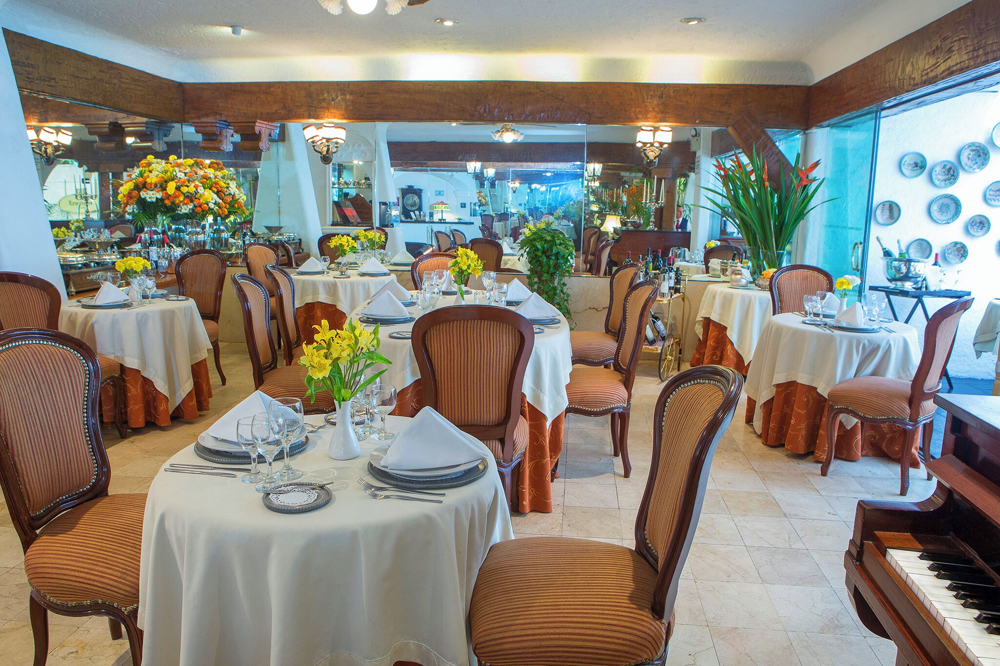 Un restaurante con varias mesas dispuestas para comer, sillas y un piano.