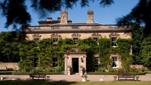 A stately building with a symmetrical facade, large windows, and a central entrance flanked by columns. - Eshott Hall (Morpeth)