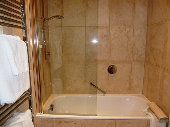 Una ducha a pie con paredes de azulejos, bañera y toallero.